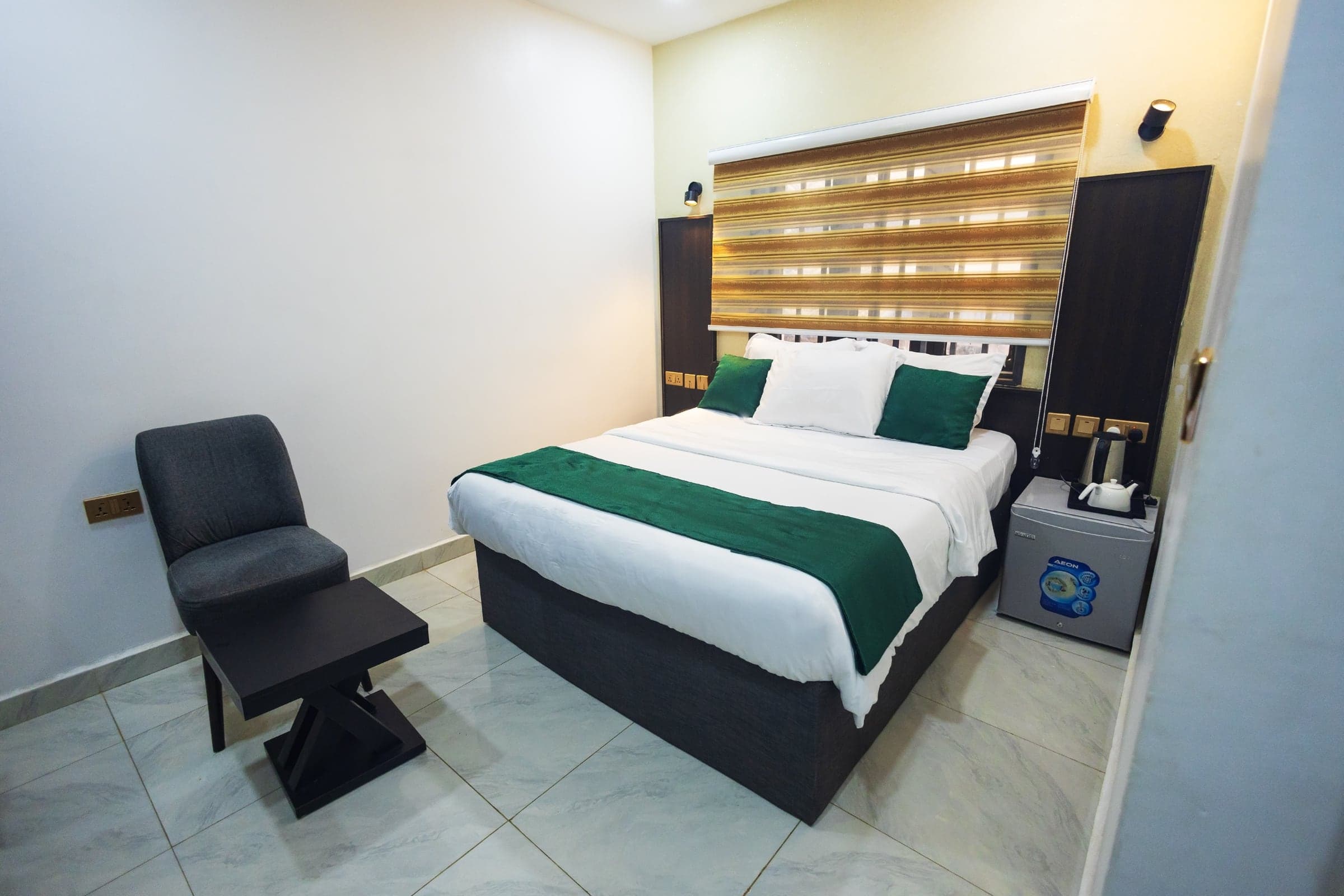 Standard Room at Diplomat Enclave Suites with a queen bed and warm, restful furnishings